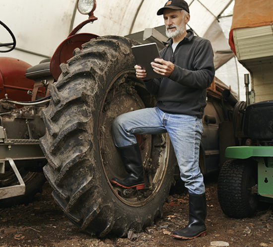 Farmer with a tractor looking at a tablet