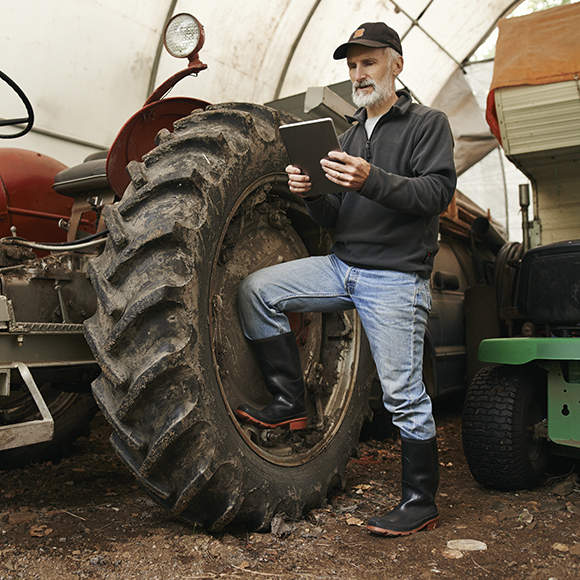 Farmer with a tractor looking at a tablet